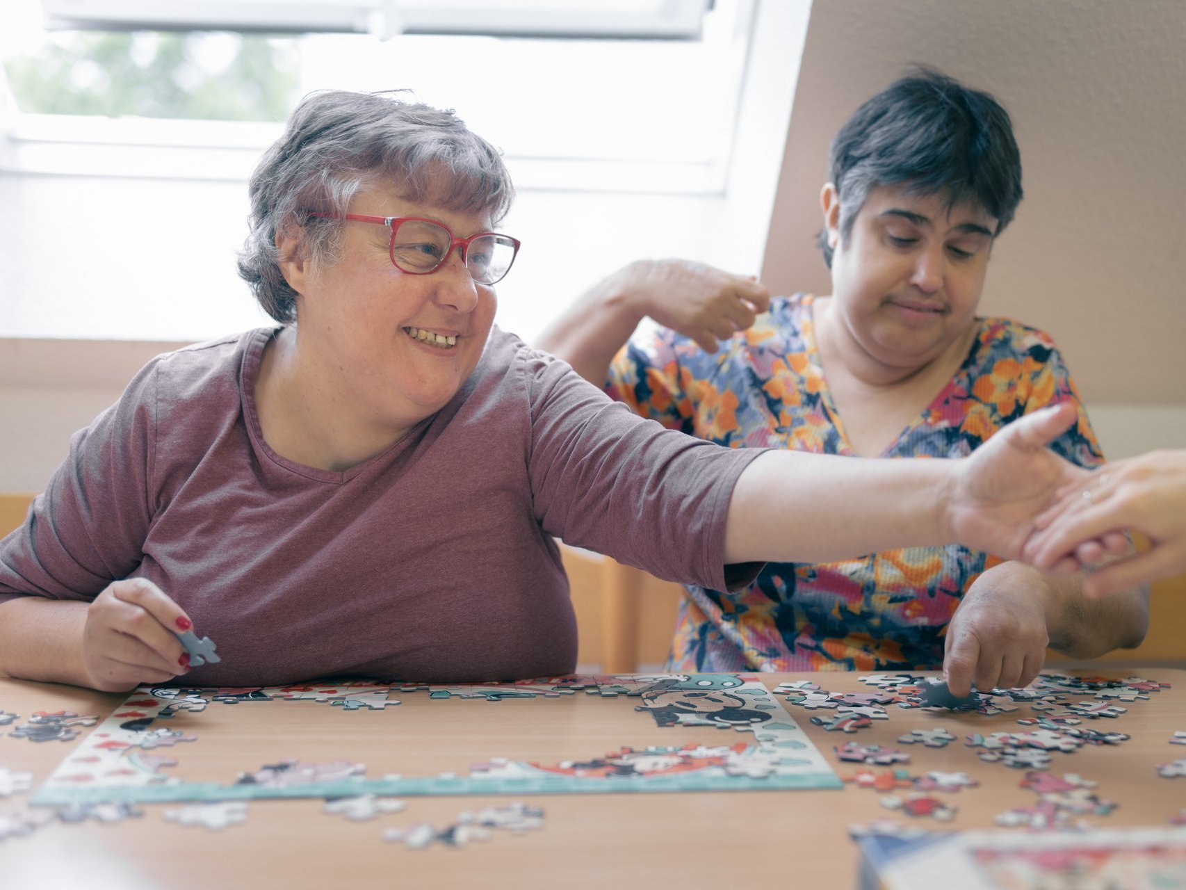 Zwei behinderte Frauen legen gemeinsam ein Puzzle zusammen