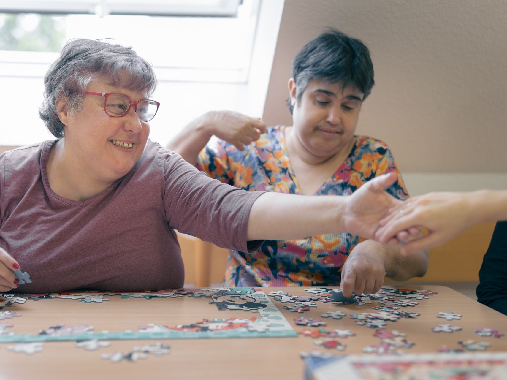 Zwei behinderte Frauen legen gemeinsam ein Puzzle zusammen