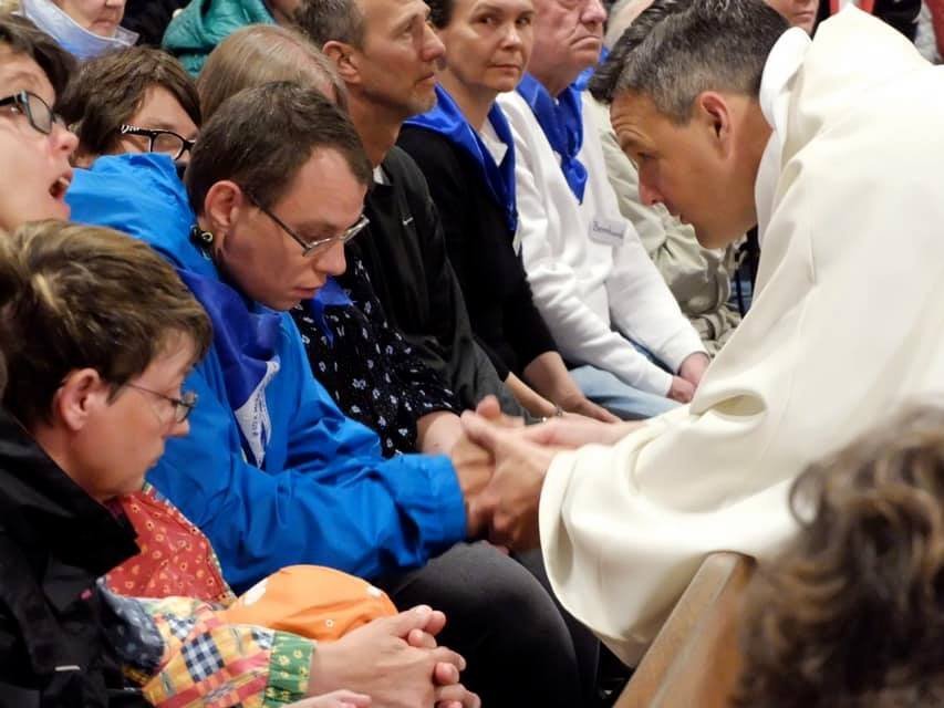 In der Kirche: Gottesdienst mit vielen Besuchern - Pater Jörg hält die Hand eines jungen Mannes