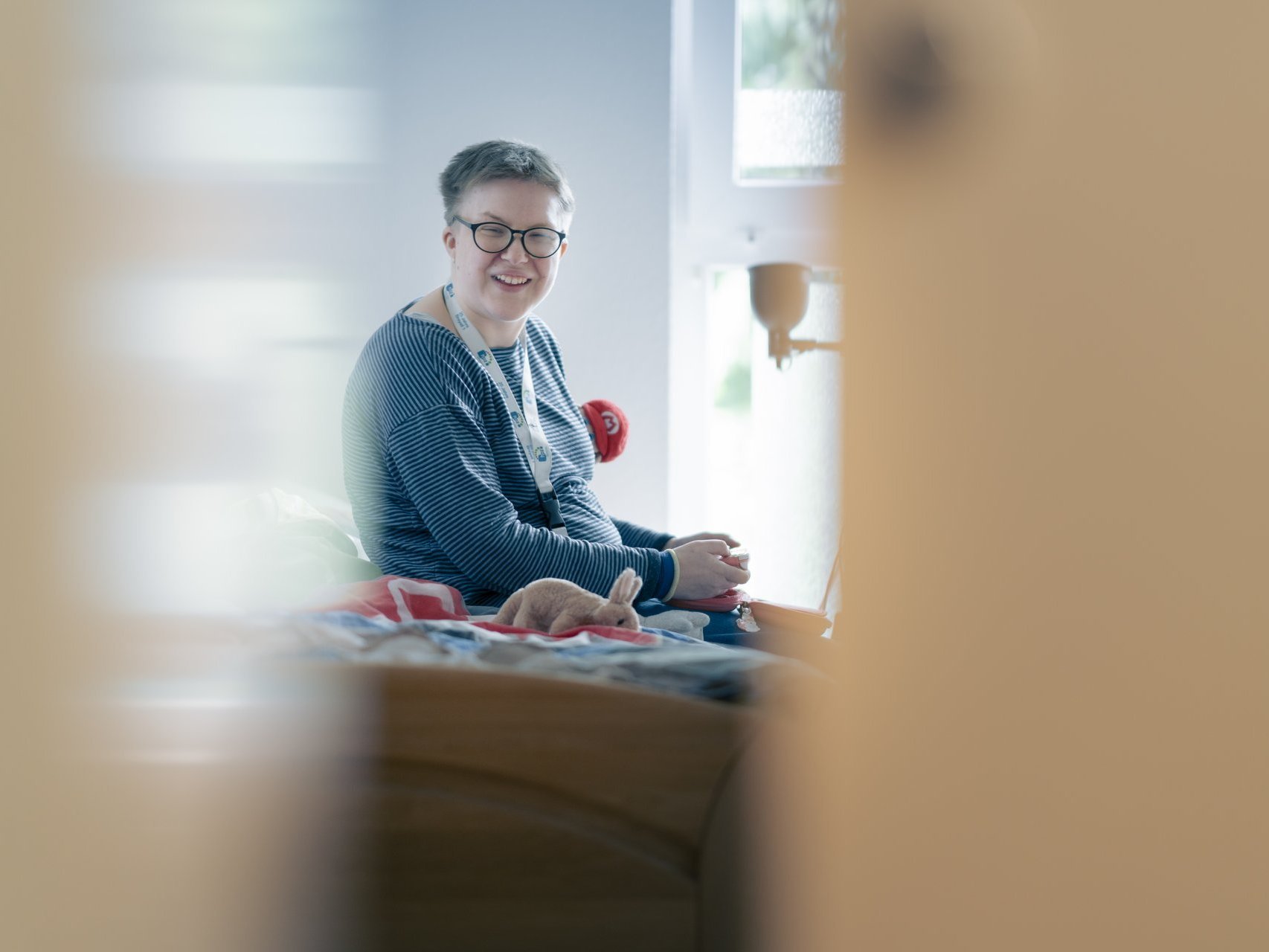 Eine Behinderte Frau sitzt auf einem Bett und lacht in die Kamera