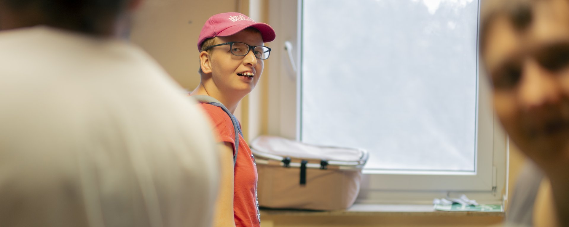 Bewohner mit pinken Cap und Brille schaut in die Kamera